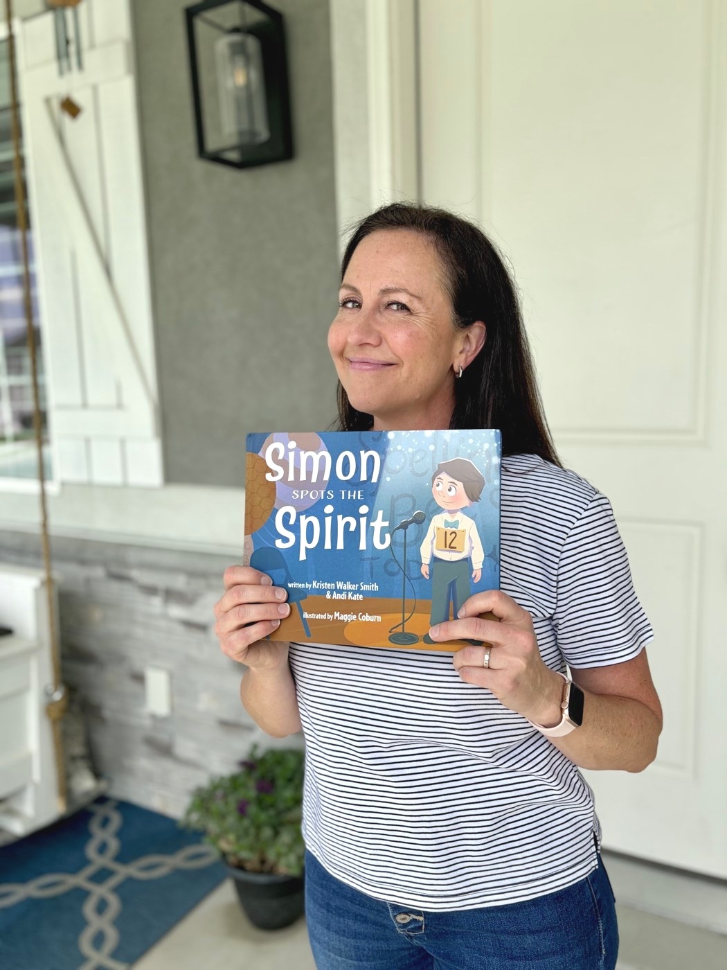 Andi Kate holding up her book, Simon Spots the Spirit